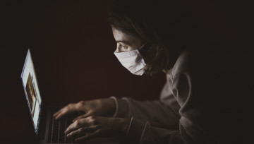 Image d'une internaute portant un masque devant son écran