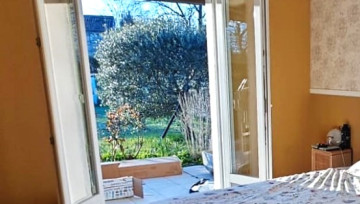 Photo d'une chambre avec fenêtre ouverte donnat sur le jardin